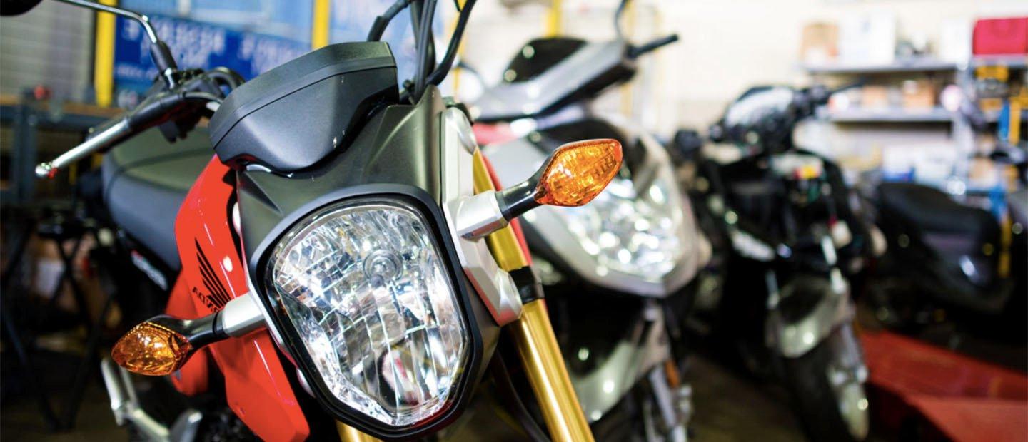 Three motorcycles lined up in a row in a garage.